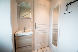 A bathroom with a sink, mirror, and a door leading to another room. - Chalet Jacobin 6p with Shared Pool, Terrace and Wi-Fi (Livarot-Pays-d'Auge)