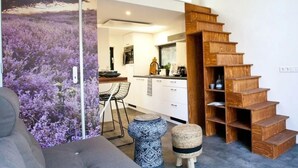 Een modern interieur met een houten trap, een keukenhoek en een eetgedeelte.