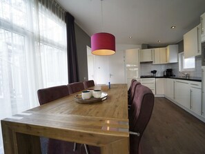 Eine moderne Küche mit weißen Schränken, einem Holzespeisetisch und einer roten Pendelleuchte.