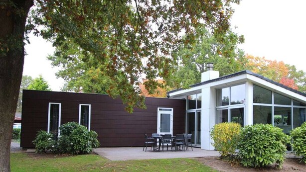 Ett modernt hus med en uteplats, en matplats och ett stort fönster.