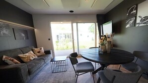 Ein modernes Wohnzimmer mit einer grauen Couch, einem runden Tisch und einem großen Fenster.