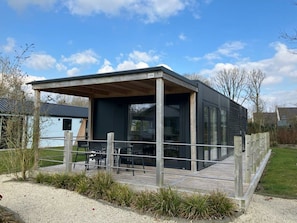 A modern house with a covered patio, large windows, and a deck. - Holiday Home in Kaatsheuvel With Terrace (Kaatsheuvel)
