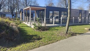 Ein modernes Gebäude mit überdachter Außenbestuhlung, großen Fenstern und einem gepflasterten Weg.