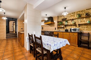 Una cocina con mesa, sillas, microondas y pared de piedra.