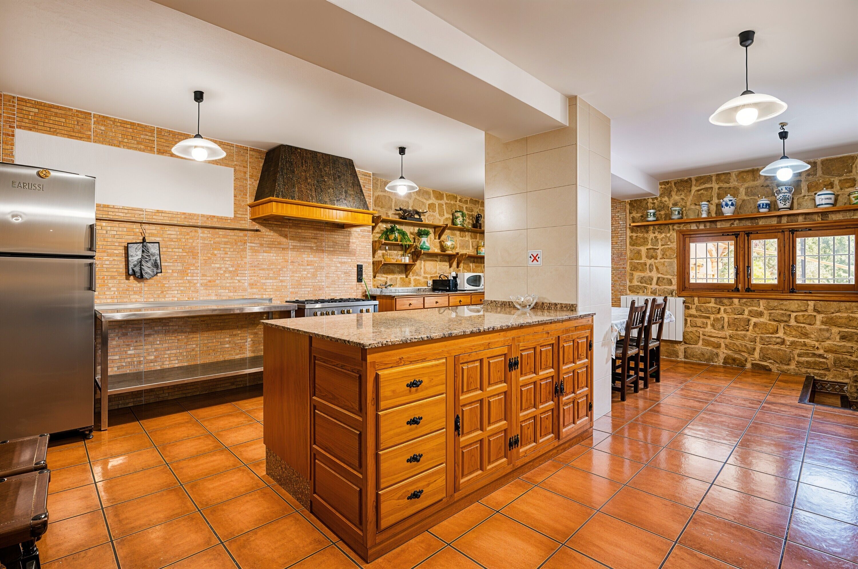 Una cocina amplia con una isla grande, un refrigerador y una pared decorativa de piedra.