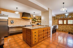 A spacious kitchen with a large island, a refrigerator, and a stone accent wall.