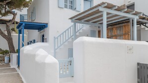 En hvid bygning med blå detaljer, herunder en trappe og en træpergola.