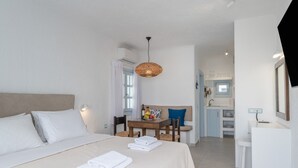 Et hotelværelse med seng, spisebord med stole, et tekøkken og et badeværelse.