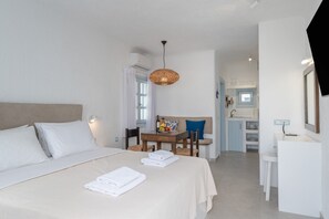 A hotel room with a bed, a dining table with chairs, a kitchen area, and a bathroom. - Mykonian Dream Studio – Pool, Beach & Luxury (Mykonos)