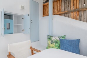 A room with a bed, a chair, a wardrobe, and a wooden wall. - Mykonian Dream Studio – Pool, Beach & Luxury (Mykonos)