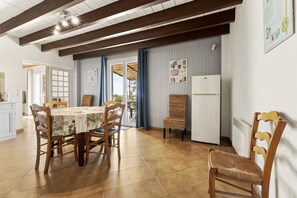 A dining area with a table, chairs, and a refrigerator. - Holiday Home 'Gîte' with Private Terrace, Wi-Fi and Air Conditioning (Saint-Gilles)