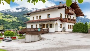 Ein zweigeschossiges Gebäude mit Balkon, einem Schild, das ein Restaurant anzeigt, und Blick auf Berge im Hintergrund.
