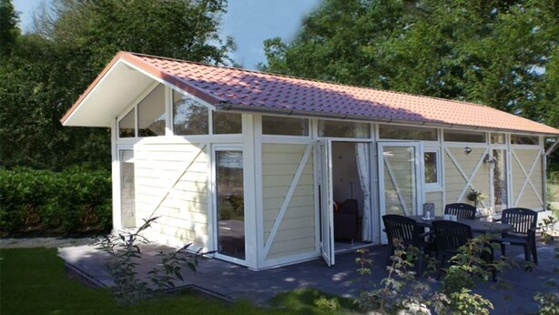 A single-story house with a red-tiled roof, large windows, and a patio with outdoor furniture. - Holiday Home in Breskens With Terrace (Breskens)