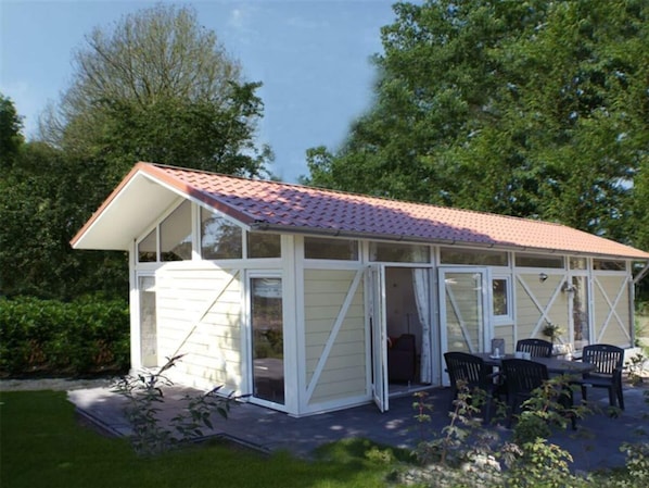A single-story house with a red-tiled roof, large windows, and a patio with outdoor furniture. - Holiday Home in Breskens With Terrace (Breskens)