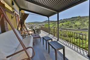 A covered outdoor seating area with a view of a green landscape and hills.