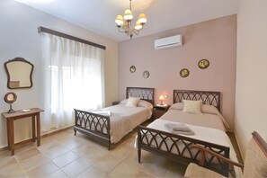 A bedroom with two beds, a bedside table, a mirror, and a chandelier.