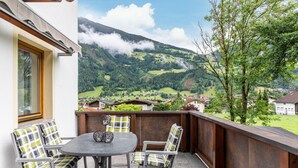 A balcony with a table and chairs, overlooking a mountainous landscape with houses. - Apartment Viktoria – Mountain Views, Terrace and Accessible Comfort (Ried im Zillertal)