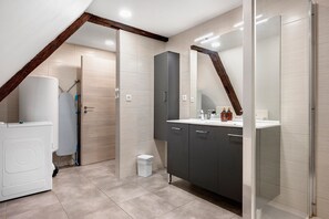 Un baño moderno con ducha, inodoro, lavamanos y espejo.