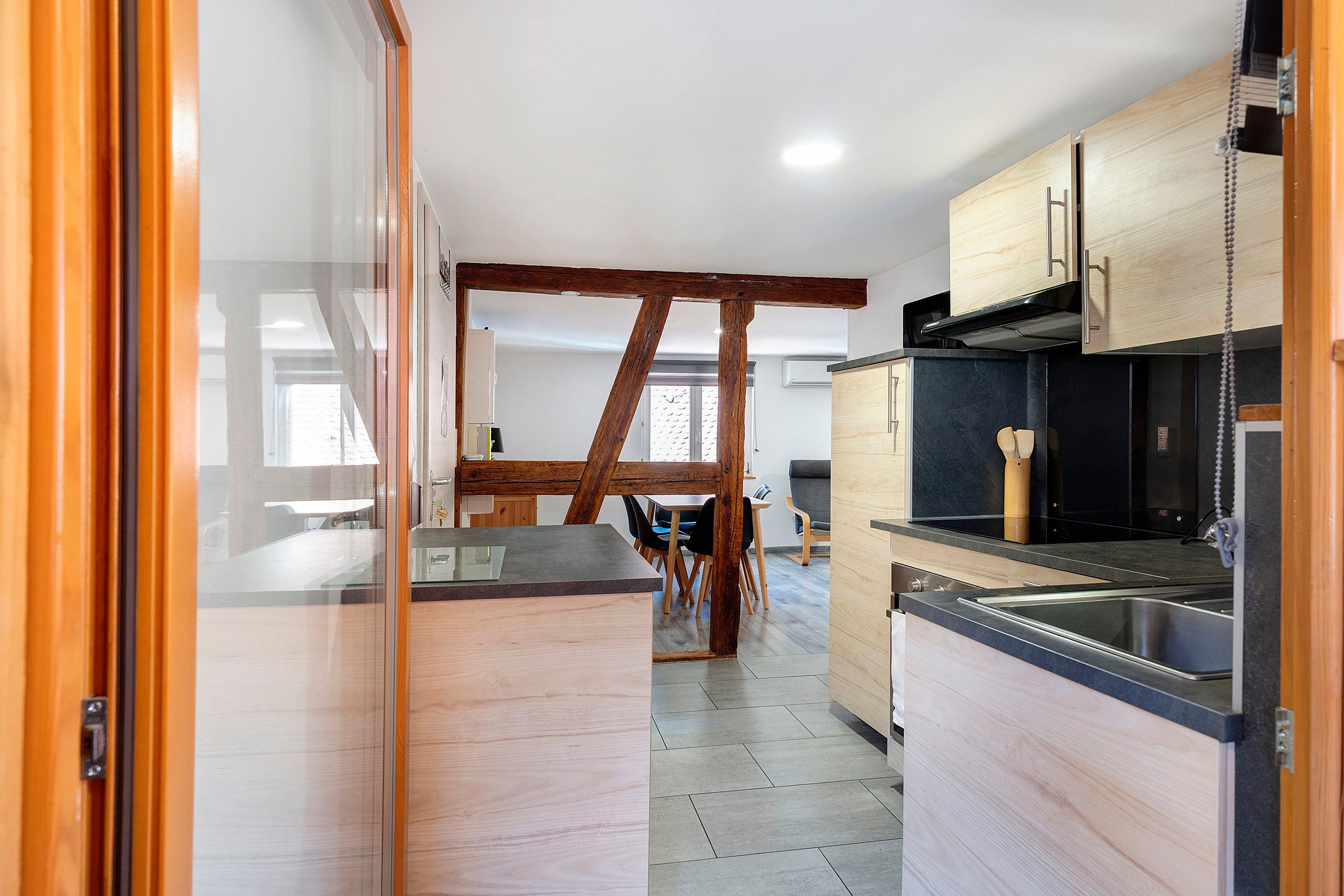 Une cuisine moderne avec des meubles en bois, un plan de travail noir et un évier en acier inoxydable.