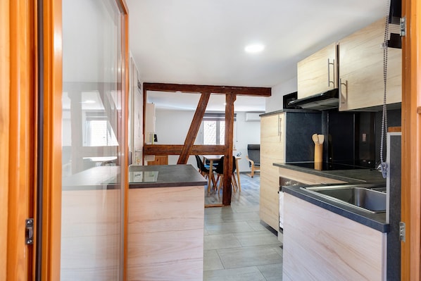 A modern kitchen with wooden cabinets, a black countertop, and a stainless steel sink.