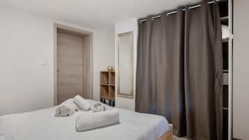 Un dormitorio con cama, armario, espejo y estante con objetos decorativos.