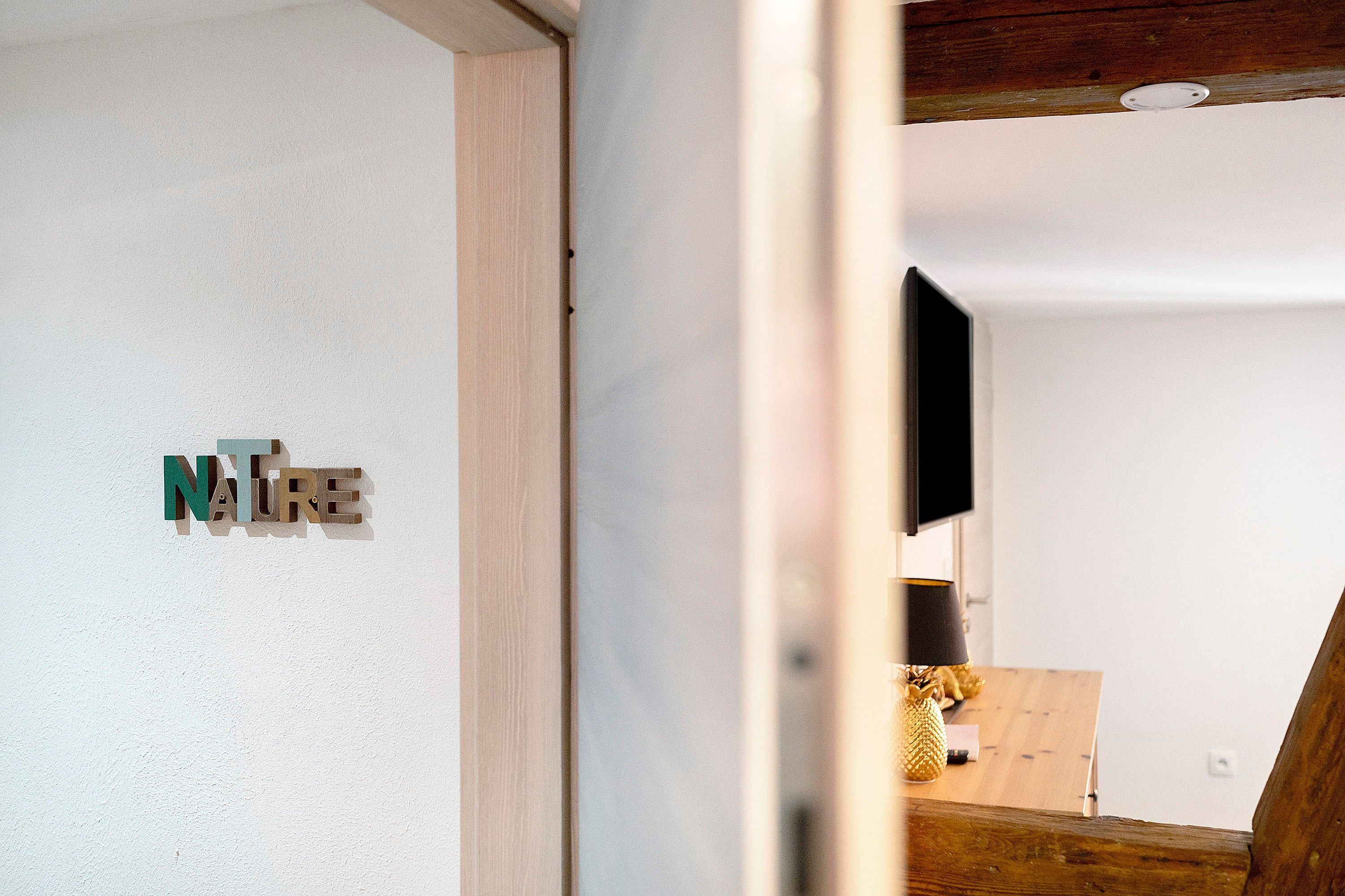 Ein Zimmer mit Holzboden, weißer Wand und einem an der Wand befestigten Fernseher.