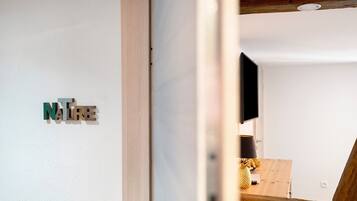 Ein Zimmer mit Holzboden, weißer Wand und einem an der Wand befestigten Fernseher.
