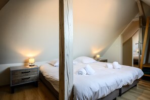A bedroom with a wooden headboard, two bedside tables with lamps, a large bed with white bedding, and a wooden floor.