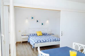 Quarto com cama, mesas de cabeceira, uma mesa e cadeiras.