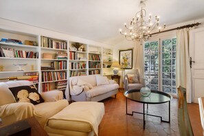 A cozy living room with a sofa, a coffee table, and a bookshelf filled with books. - Holiday Home 'L'écrin Provençal' with Private Pool, Private Terrace and Wi-Fi (Callian)
