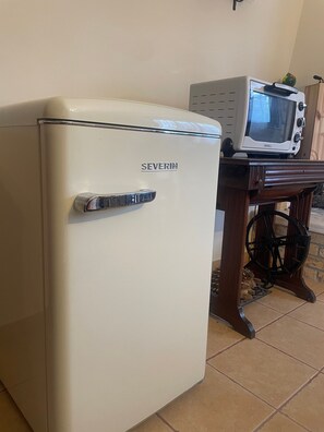 A white refrigerator with a handle, a microwave on a wooden table, and a spinning wheel. - Villa Mario – Private Hot Tub and Mountain View in Rosciano (Rosciano)