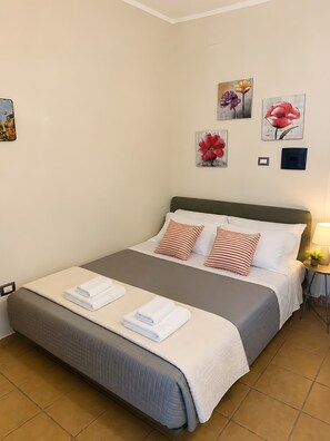 A neatly made bed with a grey and white duvet, striped pillows, and folded white towels. - Villa Mario – Private Hot Tub and Mountain View in Rosciano (Rosciano)