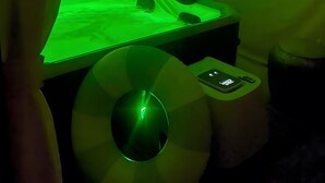 Una stanza con un letto, un tavolino e una lampada da parete verde.
