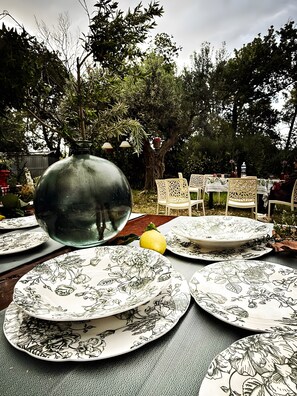 A table set outdoors with patterned plates, a large vase, and white chairs. - Villa Mario – Private Hot Tub and Mountain View in Rosciano (Rosciano)
