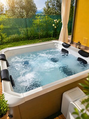 A hot tub with a pump, surrounded by greenery and a yellow wall. - Villa Mario – Private Hot Tub and Mountain View in Rosciano (Rosciano)