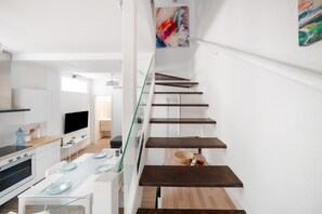 A modern kitchen with a dining area, a staircase with glass railings, and a flat-screen TV mounted on the wall. - Holiday Home 'Mirador De San Juan De Las Aguilas' with Mountain View, Wi-Fi and Air Conditioning (Aguilas)