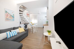 A modern living room with a grey sofa, a flat-screen TV, a staircase, and a dining area. - Holiday Home 'Mirador De San Juan De Las Aguilas' with Mountain View, Wi-Fi and Air Conditioning (Aguilas)