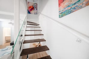 Eine moderne Treppe mit Glasgeländern und Holzstufen, die zu einem Raum mit Essbereich führt.
