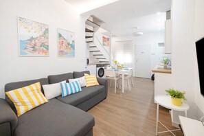 A modern living room with a grey sofa, a dining area, a staircase, and a flat-screen TV. - Holiday Home 'Mirador De San Juan De Las Aguilas' with Mountain View, Wi-Fi and Air Conditioning (Aguilas)