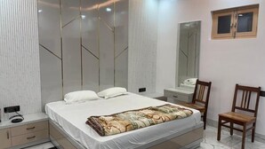 A bedroom with a bed, bedside tables, a mirror, and a chair. - Shree Laxmi Banquet & Hotel (Darbhanga)