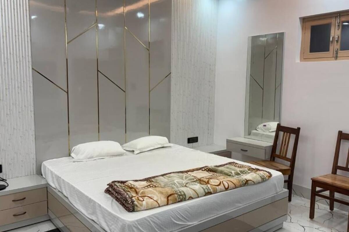Un dormitorio con cama, mesitas de noche, un espejo y una silla.