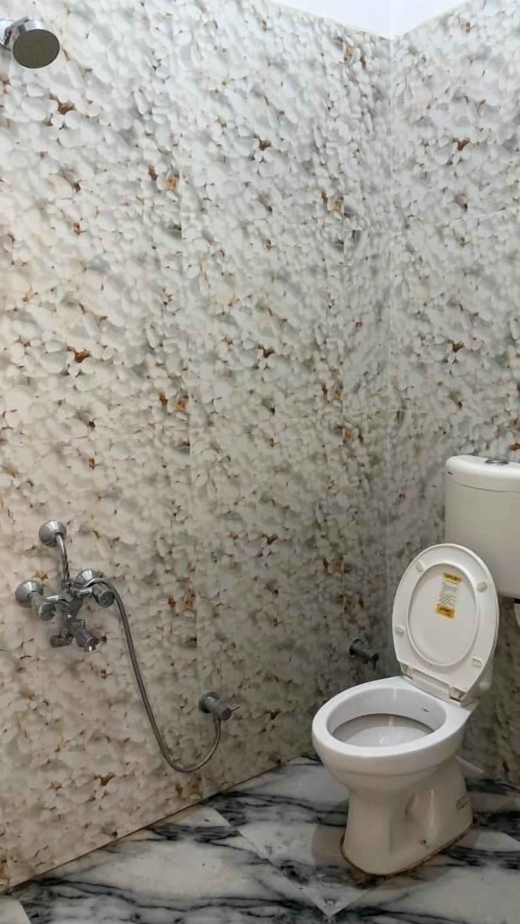 Un baño con piso de mármol, inodoro y ducha con pared de mármol.