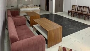 A modern living room with a sofa, coffee table, and chairs. - Shree Laxmi Banquet & Hotel (Darbhanga)