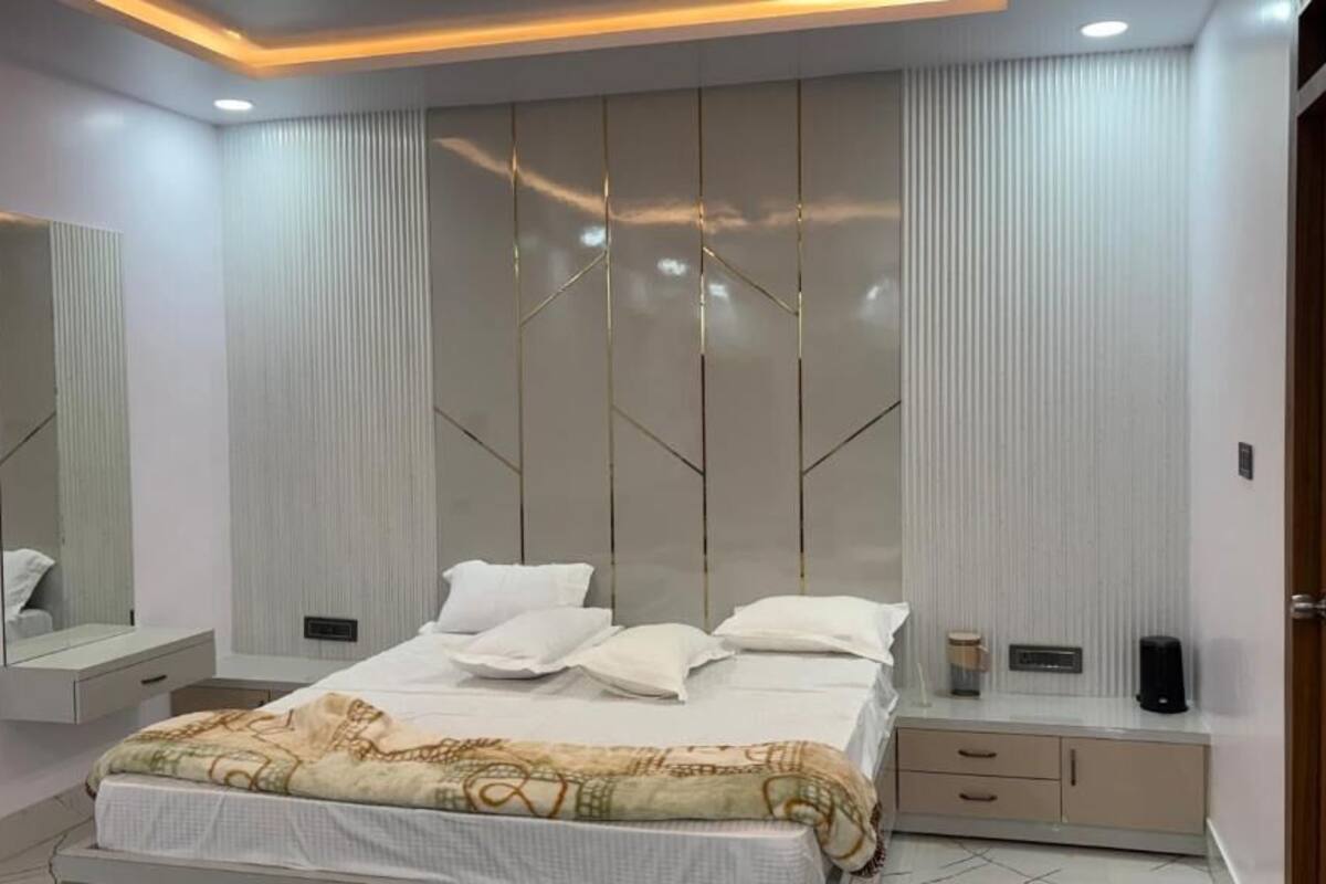 Un dormitorio moderno con una cama, mesitas de noche, un espejo y un armario.