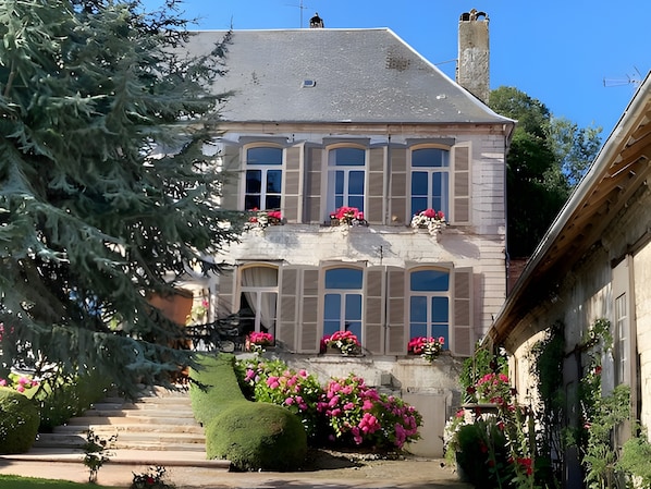 A two-story building with a stone facade, multiple windows, and a chimney.