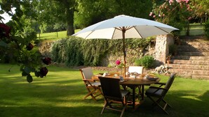 An outdoor dining area with a table, chairs, and a large umbrella.