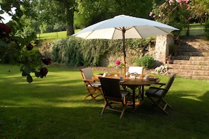 An outdoor dining area with a table, chairs, and a large umbrella.