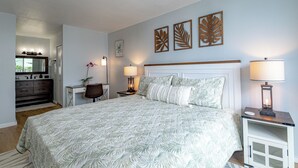 Un dormitorio con una cama grande, un escritorio, una silla, un aparador y decoración en la pared.