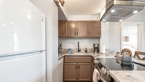 Cocina compacta equipada con refrigerador, estufa, horno y cafetera.