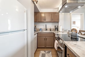 A compact kitchen with a refrigerator, stove, oven, and a coffee maker.